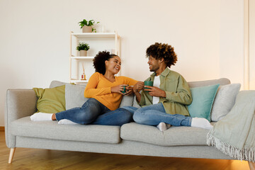 Fototapeta premium Happy Married Black Couple Talking And Drinking Coffee At Home