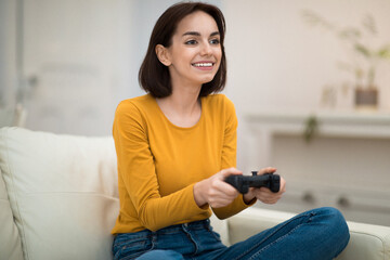 Joyful young woman playing video games alone at home