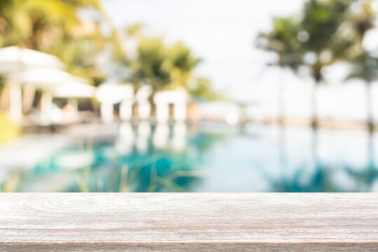 Empty wood table top and blurred swimming pool in tropical resort in summer banner background - can used for display or montage your products.