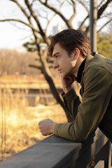 man sitting on the bench, looking on the pond in the park