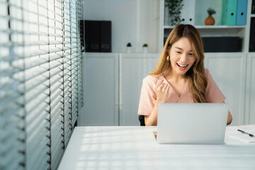 A young female employee receives a promotion, good news or finished her task and overjoyed for...