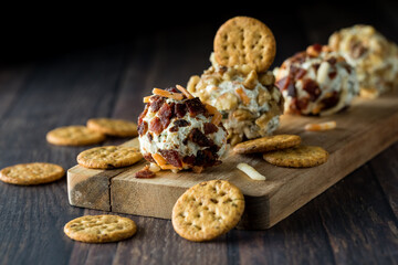 Dill pickle fat bombs surrounded by crackers, against a dark background.