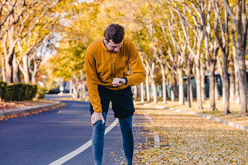 Man runner checking his pulse on the fitness tracker while exercising outdoors