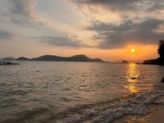 Sunset on the sea of Thailand beach. The sky in the rays of the sun. The sun is setting Sandy sand on the beach. Stones on the beach. lunar path from the sun to the sea. Beautiful mountains in the sea