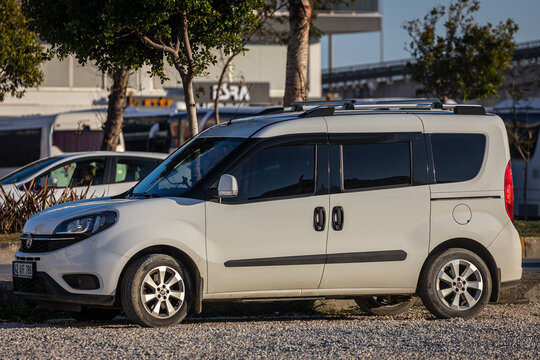 Side, Turkey -February 13, 2023:  white Fiat Doblo   is parked  on the street on a warm summer day against the  road and trees