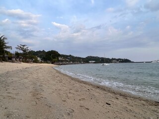 Thai beach Nai Harn. Yellow sand and the sea Sunbathing people on the beach under an umbrella.