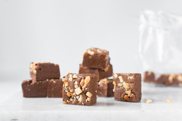 chocolate fudge with nuts on a marble tray, chocolate fudge cut into pieces, fudge candy on a marble tray