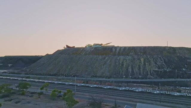 Sunrise high angle aerial drone flight over a big open pit silver, zinc and lead mine (orebody called line of lode) and a miner&rsquo;s memorial and visitors centre located in Broken Hill, New South Wales