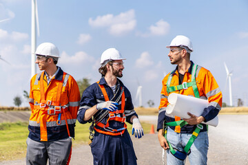 Front view of three caucasian engineers in uniform and hardhat talk about system installation at agricultural field with wind turbines, wind turbine generate electricity, Renewable energy