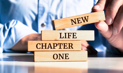 Close up on businessman holding a wooden block with "New Life Chapter One" message