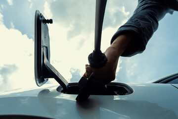 Progressive concept of electric rechargeable car, hand inserting charger device from electric...
