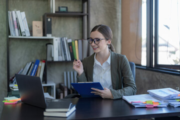 Smiling professional businesswoman working with a laptop in an office.