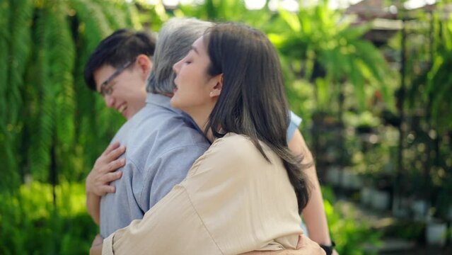 Asian family relationship and old people health care concept. Adult couple meeting and hugging elderly father at plant shop. Retired man enjoy outdoor activity with daughter and son on summer vacation
