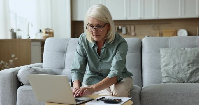 Upset mature woman planning personal budget, review savings and expenses feels stressed having overspend, unpaid bills, huge taxes and high electricity rates, insufficient pension to pay utilities
