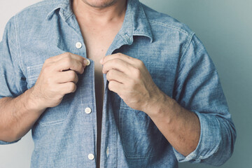 Wrong first button the rest shall be wrong concept. Man buttoning up blue jeans shirt. Studio shot...