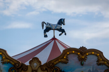 Wooden horse on the roof of a merry-go-round with blue sky with clouds in the background