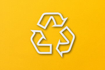 White paper cut into recycled shapes isolated on yellow paper background.