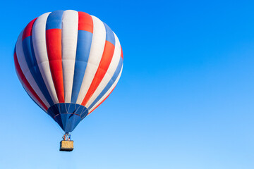 white blue and red hot air balloon against the blue sky