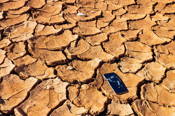 desert area, cracks on dry soil. broken old smartphone on the ground