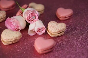 Heart-shaped macarons with roses on glittery pink background, Valentines day