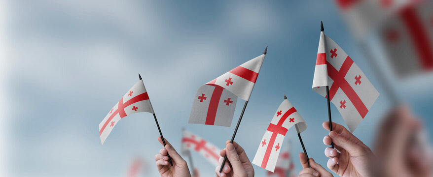 A group of people holding small flags of the Georgia in their hands