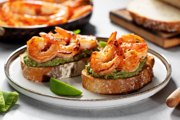 Toast or sandwich with Grilled fresh Spicy Prawns Shrimps with mashed avocado and lime slices.