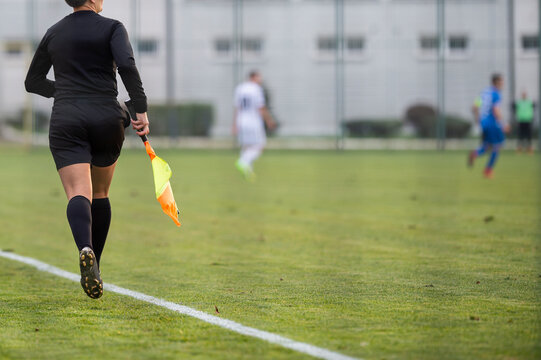 A female assistant referee runs by the touchline