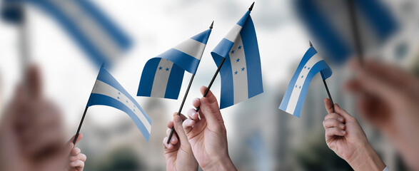 A group of people holding small flags of the Honduras in their hands
