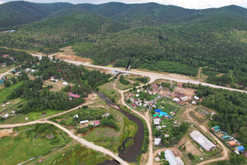 Aerial view of the village among the coniferous forest. Countryside in summer. 