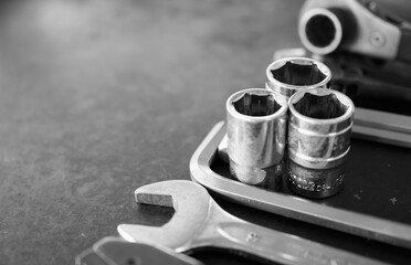 Hand tools consisting of wrenches, pliers, socket wrenches, laid out on old steel plate background.