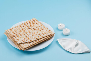 Matzah and Shabbat candles and Jewish kippah on blue background. Pesah Passover holiday celebration dinner concept.