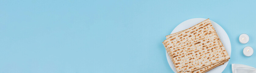 Matzah and Shabbat candles and Jewish kippah on blue background. Pesah Passover holiday celebration dinner concept.