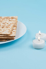 Matzah and Shabbat candles on blue background. Pesah Passover holiday celebration dinner concept.
