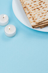 Matzah and Shabbat candles on blue background. Pesah Passover holiday celebration dinner concept.