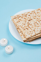 Matzah and Shabbat candles on blue background. Pesah Passover holiday celebration dinner concept.