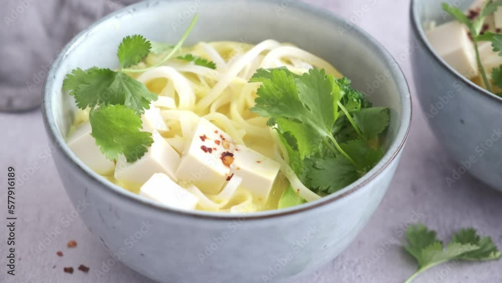 Wall mural Vegan laksa with rice noodles, broccoli and tofu in blue bowls, gray background.