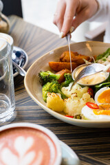 Healthy food concept. Top view young woman tasting salad breakfast. Business lunch time concept. Close up of a cafe visitor holding cutlery and tasting delicious healthy food served