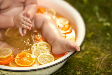 A little girl bathes in a bowl of fresh lemons and oranges in nature during sunset. The concept of healthy and clean eating. Fruits and vegetables. natural vitamins - fresh lemons and oranges.​