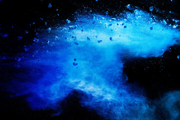 Split debris of  stone exploding with blue powder against black background.