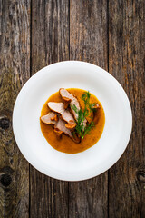 Fried veal loin in chanterelle mushrooms sauce on wooden table

