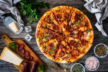 Circle pizza chorizo  with chicken nuggets and mozzarella, on wooden table
