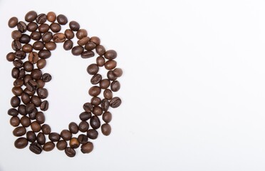 D is a capital letter of the English alphabet made up of natural roasted coffee beans that lie on a white background. Plenty of space to put text or pictures, top view and studio photography.