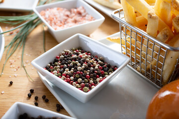 A view of a condiment cup of a mixture of different colored peppercorns.