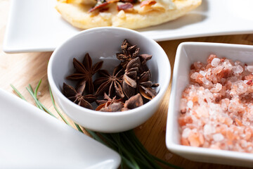 A view of a condiment cup of star anise, next to Himalayan pink rock salt.