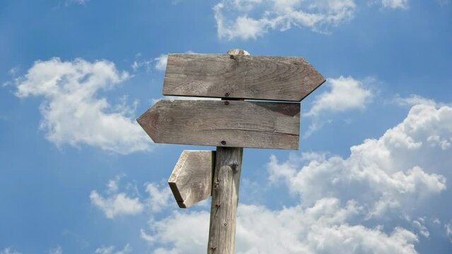 travel destinations options. Direction road sign with wooden arrows on sky and clouds in movement