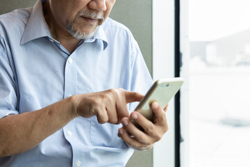 Obraz na płótnie Canvas Hand of old asian senior man using smartphone, Closeup shot