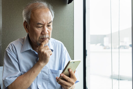 Serious old asian senior man using smartphone, thinking, planning or having problem