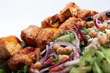 A closeup view of an entree of chicken kebabs and salad.