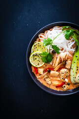Tom Yum - Thai soup with chicken breast nuggets and noodles on wooden table

