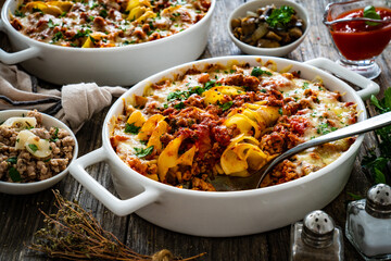Noodle casserole with minced meat, mozzarella cheese and vegetables on wooden table
